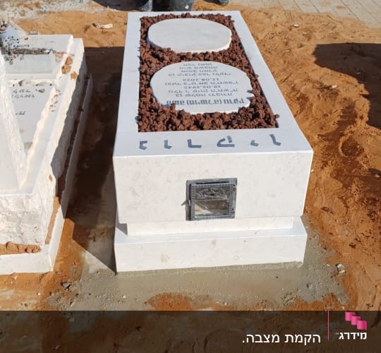 מצבה מעוצבת משיש בהיר עם אבני טוף ובית נר מובנה בחזית